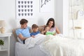 Happy family reading book together in bedroom Royalty Free Stock Photo