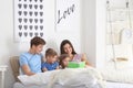 Happy family reading book together in bedroom Royalty Free Stock Photo