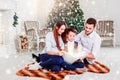 Happy family reading Christmas fairy tales near the Xmas tree. Living room decorated by Christmas tree and present gift box Royalty Free Stock Photo