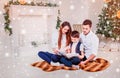 Happy family reading Christmas fairy tales near the Xmas tree. Living room decorated by holiday tree and present gift box Royalty Free Stock Photo