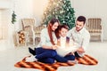 Happy family reading Christmas fairy tales near the Xmas tree. Living room decorated by Christmas tree and present gift box Royalty Free Stock Photo