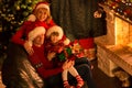 Happy family in red hats with gifts sitting at Royalty Free Stock Photo