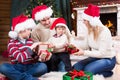 Happy family in red hats with gifts sitting at Royalty Free Stock Photo