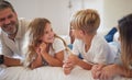 Happy family relax on a bed, kids, smile and playing in a bedroom together. Young loving parents enjoying free time with Royalty Free Stock Photo