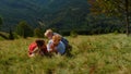 Happy family relaxing grass mountain slope. Parents lying meadow with children.