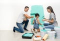 Happy family renovating their new home.Father sitting near daughter, smiling painting with a roller and looking at camera Royalty Free Stock Photo