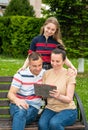 Happy family resting in the park and using tablet PC outdoors Royalty Free Stock Photo