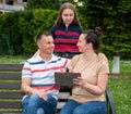 Happy family resting in the park and using tablet PC outdoors Royalty Free Stock Photo