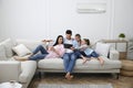 Happy family resting under air conditioner on white wall at home Royalty Free Stock Photo