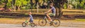 Happy family is riding bikes outdoors and smiling. Father on a bike and son on a balancebike BANNER, long format Royalty Free Stock Photo