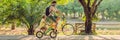 Happy family is riding bikes outdoors and smiling. Father on a bike and son on a balancebike BANNER, long format Royalty Free Stock Photo