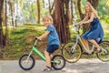 Happy family is riding bikes outdoors and smiling. Mom on a bike and son on a balancebike Royalty Free Stock Photo