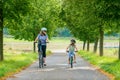 Happy family is riding bikes outdoors and smiling. Mother and daughter, cute little preeschool girl on bicycles, active leisure Royalty Free Stock Photo