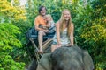 Happy family riding on an elephant, woman sitting on the elephant`s neck