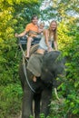 Happy family riding on an elephant, woman sitting on the elephant`s neck