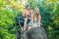 Happy family riding on an elephant, woman sitting on the elephant`s neck