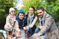 Happy family roasting marshmallow over campfire Royalty Free Stock Photo