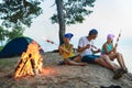 Happy family roasting sausages over campfire. camping and tourism concept