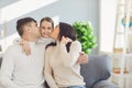 Happy family in the room. Mother and father kiss a daughter sitting on a sofa in a bright sunny room at home Royalty Free Stock Photo