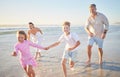 Happy family running on the beach with mother, father and children holding hands for summer holiday, wellness and Royalty Free Stock Photo