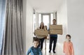 Happy family running in hall. Funny kids jumping  with carton box, parents laughing Royalty Free Stock Photo