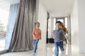 Happy family running in hall. Funny kids jumping  with carton box, parents laughing Royalty Free Stock Photo