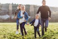 Father, mother and children run through a green field. Royalty Free Stock Photo