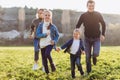 Happy family runs across the field. Father, mother and children run through a green field. Royalty Free Stock Photo