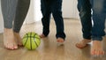 Happy family's feet as they kick a football back and forth on a wooden floor in a house corridor