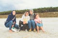 Happy family on a sandy beach - mother with three daughters sitting on a tree trunk Royalty Free Stock Photo