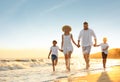 Happy family on sandy beach near sea at sunset