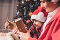 Happy family in Santa hat, father and child son giving Christmas gift at home. Sitting on a couch in the living room with puppy Royalty Free Stock Photo