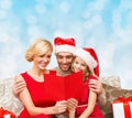 Happy family in santa hats with greeting card Royalty Free Stock Photo
