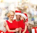 Happy family in santa hats with greeting card Royalty Free Stock Photo