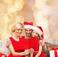 Happy family in santa hats with greeting card Royalty Free Stock Photo