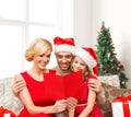 Happy family in santa hats with greeting card Royalty Free Stock Photo