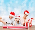 Happy family in santa helper hats packing gift Royalty Free Stock Photo