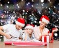 Happy family in santa helper hats packing gift Royalty Free Stock Photo