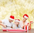 Happy family in santa helper hats packing gift Royalty Free Stock Photo