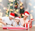 Happy family in santa helper hats packing gift Royalty Free Stock Photo