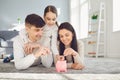 Happy family saves money in a piggy bank pig.