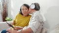 Happy family senior couple wearing headphones listening music and watching tablet to social media while man kiss to cheek. Royalty Free Stock Photo