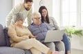 Happy family of senior old parents and adult son and daughter sitting at home using laptop Royalty Free Stock Photo