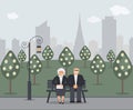 Happy family seniors: cute smiling elderly man and woman with clutch bag are sitting on bench in park. Retired elderly couple in