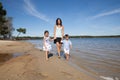 family of single mother, and two child, son daughter walking holding hands in the sea sand of a sunny beach Royalty Free Stock Photo