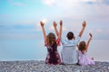 Happy family sitting on beach lifted hand