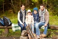 Happy family sitting on bench at camp fire Royalty Free Stock Photo