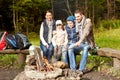 Happy family sitting on bench at camp fire Royalty Free Stock Photo