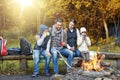 Happy family sitting on bench at camp fire Royalty Free Stock Photo