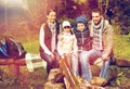 Happy family sitting on bench at camp fire Royalty Free Stock Photo